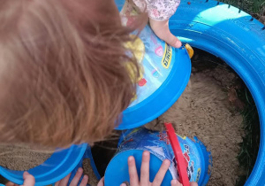 Przesypywanie piasku do niebieskiej opony.