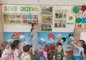 Dziewczynka wskazuje ilustrację lasu.