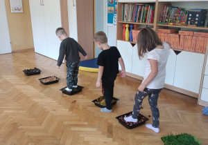 Dzieci idą po ścieżce sensorycznej z darów jesieni.