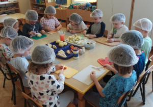 Dzici kroją warzywa do sałatki warzywnej.