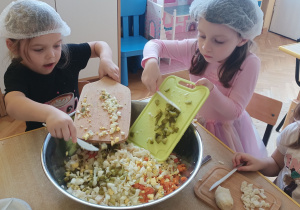 Dziewczynki zsypują pokrojone składniki do miski.