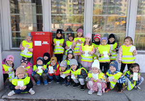 Grupowe zdjęcie przed budynkiem poczty.