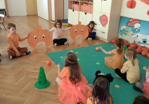 Dwie dziewczynki celują piłeczkami do dyń.