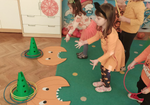 Dwie dziewczynki rzucają obręcze na pachołki.