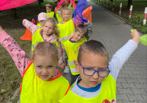 Dzieci podczas spaceru machają kolorowymi chustkami