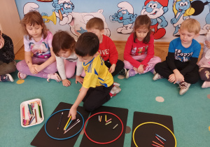 Chłopiec segreguje kredki wg rodzaju.