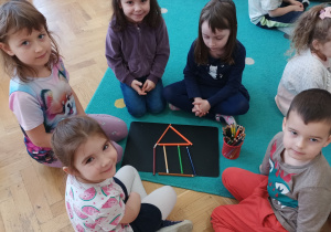 Dzieci układają z kredek domek.