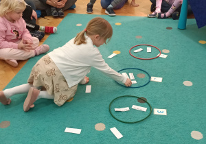 Dziewczynka wkłada napis do obręczy.