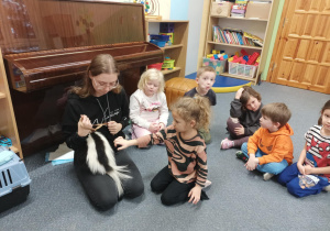 Dziewczynka głaszcze skunksa.