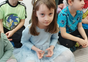 Dziewczynka ogląda mrówkę w powiększeniu.