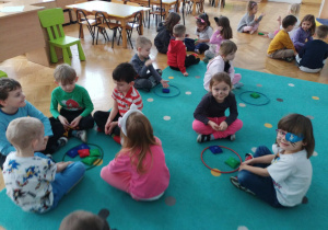 Dzieci siedzą przy obręczach z woreczkami.