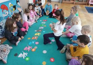 Dziewczynka dopasowuje piłkę oznaczoną kropkami do kotka oznaczonego cyfrą.