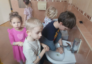 Chłopiec moczy ręce w wodzie.