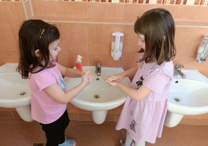Dwie dziewczynki myją dłonie.