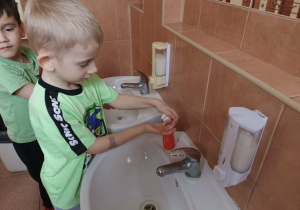 Chłopiec korzysta z dozownika mydła.