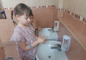 Dziewczynka myje przestrzenie między palcami.