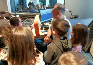 Dzieci obserwują pracę dziennikarza.