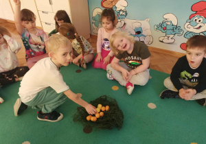 Chłopiec układa jajka w gnieździe.