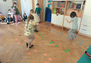 Dzieci skaczą po śladach dinozaurów.