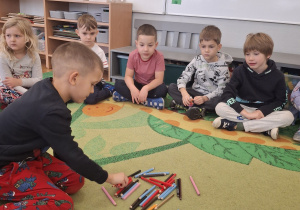 Chłopiec segreguje kredki według koloru