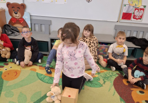 Dziewczynka układa misia obok pudełka