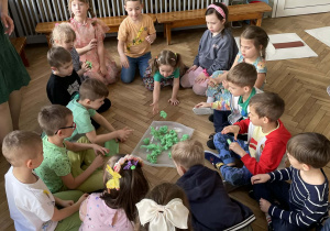 Dzieci tworzą pąki z zielonej bibuły.