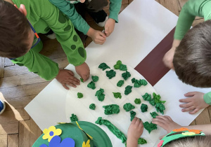 Dzieci naklejają pąki na wiosenne drzewo.