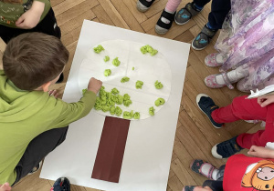 Kolejna grupa nakleja pąki na wiosenne drzewo.