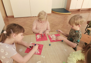 3 dzieci wykonuje orła białego z piór.