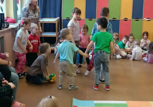 Przedszkolaki tańczą w kółeczku z młodszymi kolegami.