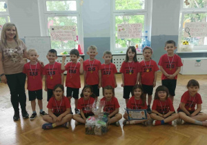 Grupowe zdjęcie z medalami, dyplomem i nagrodami.