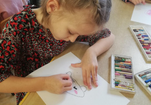 Dziewczynka rysuje portret swojego misia