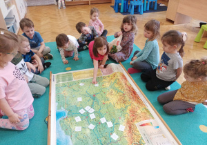 Dzieci losują obrazki przedstawiające negatywny wpływ na klimat i układają je na mapie Europy.