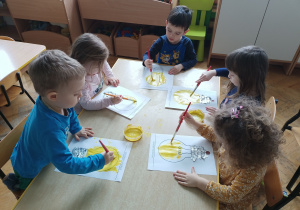 Dzieci malują farbami żarówki.