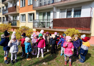 Dzieci stoją przy kwitnących krzakach forsycji.