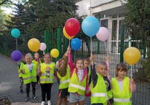 Grupa Motylków stoi z balonami przed przedszkolem.