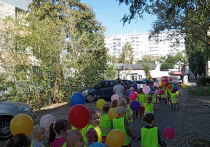 Dzieci spacerują po osiedlu niedaleko przedszkola.